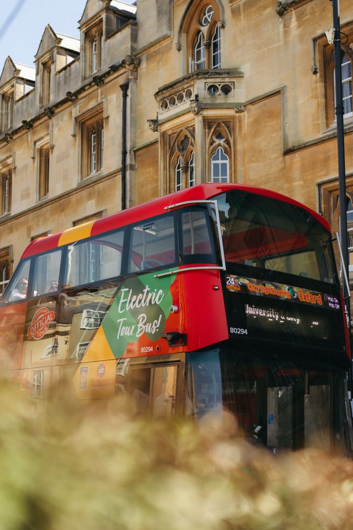 Red double-decker bus on a street in historic Oxford, capturing the essence of English architecture.